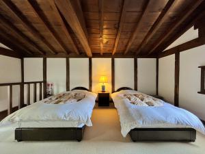 2 camas en una habitación con una lámpara en una mesa en Guest House Shimoze Agematsu, en Iida