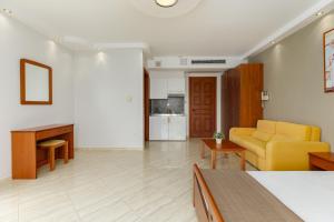 Agyra Seaview Hotel by Panel Hospitality في نيوي بوروي: غرفة معيشة مع أريكة صفراء وطاولة