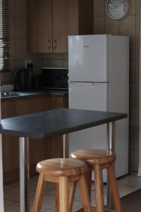 a kitchen with a table and two stools and a refrigerator at 27 on Gunn Street in Bloemfontein