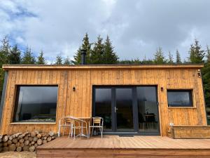 a house with glass doors and chairs on a deck at Heaven`s cabins in Tău Bistra