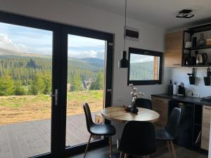 a kitchen with a table and chairs and a large window at Heaven`s cabins in Tău Bistra +6 photos