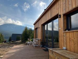 a wooden deck with chairs and tables on a building at Heaven`s cabins in Tău Bistra