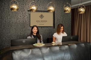 Due donne sedute a un tavolo con computer portatili di Hotel Memories Budapest a Budapest