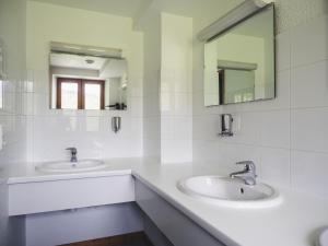 a white bathroom with two sinks and a mirror at Auberge Le Valezan in Valezan