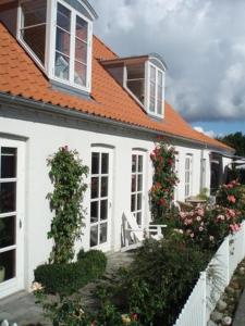 a white house with an orange roof and flowers at Balliwood værelsesudlejning in Ballen