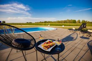 a table with a plate of food and two glasses of wine at Holiday House Drava Relax in Pitomača