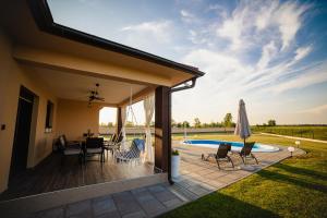 a patio with a table and chairs next to a pool at Holiday House Drava Relax in Pitomača