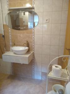 een badkamer met een wastafel en een spiegel bij Gréti Apartman in Sárospatak