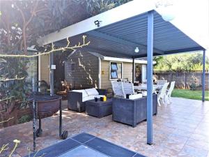 a pergola with chairs and a table on a patio at Rudys Guesthouse in Meyerton