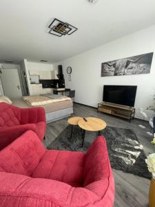 SWID Appartement في ديلتزش: غرفة معيشة بها كنبتين حمراء وسرير