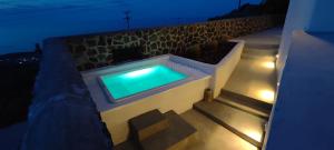 - une piscine sur le côté du bâtiment la nuit dans l'établissement Alios villa, à Imerovigli