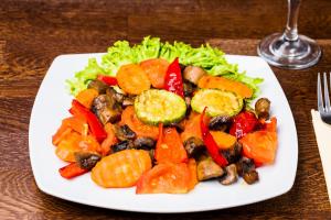 un plato de comida con verduras en una mesa en Pensiunea Restaurant Vándor, en Cîmpu Cetăţii