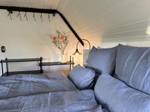 Una cama con sábanas azules y un jarrón de flores. en Loft32, en Nordstrand