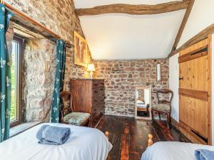 a bedroom with two beds and a brick wall at Haytongate Barn in Walton
