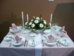 una mesa con mantel blanco con platos y velas en Hotel Brückenschänke en Sebnitz