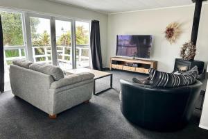 a living room with two couches and a tv at The Tirau Cottage - Waikato in Tirau