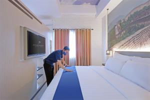 a man making a large bed in a hotel room at Premiere Hotel Tegal in Tegal