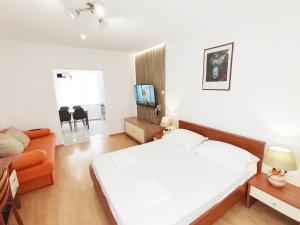 a bedroom with a bed and a living room at Apartmani Buljubašić in Baška Voda