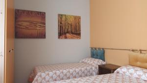 a room with two beds and two pictures on the wall at B&B Vistamare in Villa San Giovanni