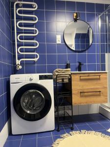 y baño de azulejos azules con espejo y lavadora. en Apartament Soplicy 17 en Toruń