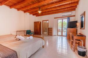 a bedroom with two beds and a desk and a television at XENIA HOTEL in Sfakia
