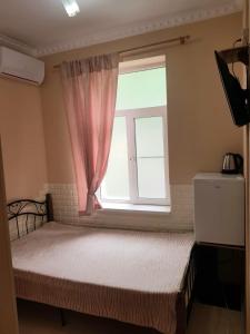 a bedroom with a bed with a pink window at Guest House Gorny Ruchei in Gagra