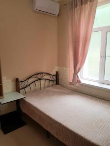 a bed in a room with a window and a bed sidx sidx sidx at Guest House Gorny Ruchei in Gagra