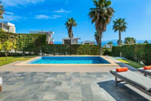 a swimming pool in a yard with palm trees at Aegean Sea View Villa in Pefkochori