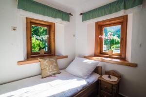 Cama pequeña en habitación con 2 ventanas en Estate Žagmeštri, en Ljubno