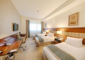 een hotelkamer met 2 bedden en een bureau bij Makkah Al Aziziah in Mekka