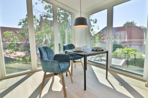 a dining room with a table and chairs and large windows at Lüttjeod - Apartment 11 in Langeoog