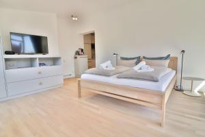 ein weißes Schlafzimmer mit einem Bett und einem TV in der Unterkunft Lüttjeod - Apartment 11 in Langeoog