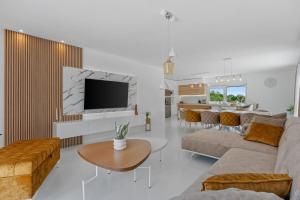 a living room with a couch and a tv and a table at NEW Villa Begovina with a private pool, Hot-Tub, 4 bedrooms in Krivodol