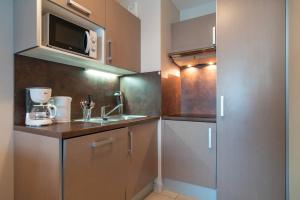 eine kleine Küche mit Spüle und Mikrowelle in der Unterkunft Les Sables 504 - Appt avec piscine partagée in Concarneau + 3 Fotos