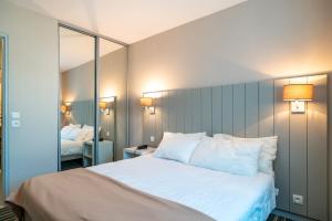 ein Schlafzimmer mit einem großen Bett und weißen Kissen in der Unterkunft Les Sables 504 - Appt avec piscine partagée in Concarneau