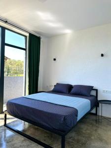Schlafzimmer mit einem Bett mit blauer Bettwäsche und einem Fenster in der Unterkunft HeyShekvetili in Shekhvetili
