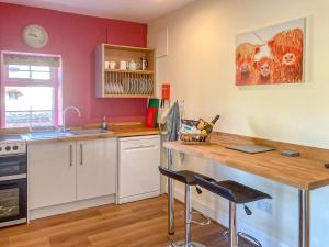 a kitchen with a wooden table and a counter top at The Grooms Cottage in Mauchline