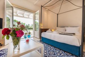 - une chambre avec un lit et un vase de fleurs sur une table dans l'établissement Donna Coraly Country Boutique Hotel, à Arenella