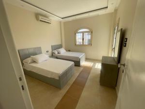 1 dormitorio con 2 camas y ventana en Moubark 6 Villa 1, en Hurghada