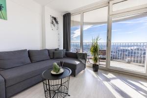a living room with a couch and a large window at Arbio I Balcony Apartments Augsburg in Augsburg