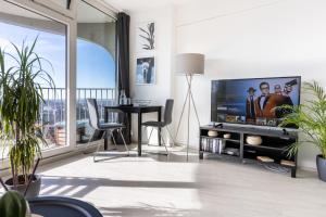 a living room with a television and a table and chairs at Arbio I Balcony Apartments Augsburg in Augsburg