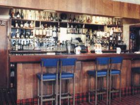 a bar with blue bar stools in a room at Willowbank Hotel in Largs