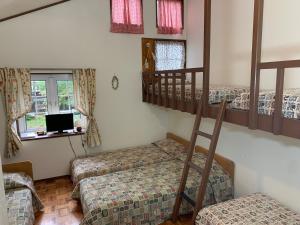 a room with three bunk beds and a television at Pension Rapport in Tambara Plateau in Numata