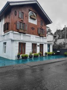 a white building with windows and plants in front of it at The Golf Green City Bungalow in Nuwara Eliya