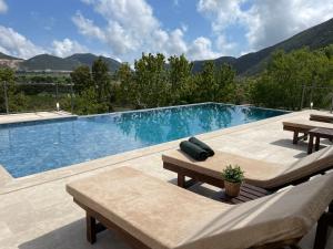 a large swimming pool with two tables and benches at Bezirgan Inn Kalkan in Islamlar