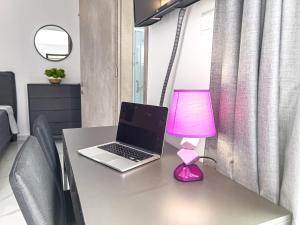 un ordinateur portable sur un bureau avec une lampe rose dans l'établissement Giorgis Luxury Apartments, à Ayia Napa 21 autres photos