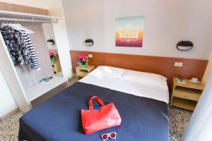 una camera da letto con un letto con una borsa rossa e occhiali da sole di Hotel Byron solo per giovani a Riccione