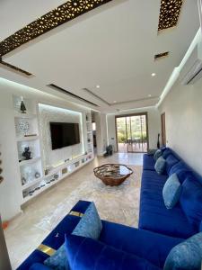 sala de estar con sofá azul y TV en Prestigia 3 chambres piscine, en Marrakech