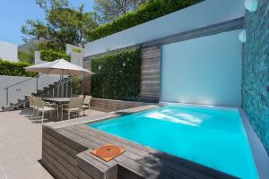 a swimming pool in a backyard with a table and an umbrella at Albert Road 14 in Cape Town