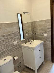 ein Badezimmer mit einem Waschbecken, einem Spiegel und einem WC in der Unterkunft Casa LiaLara Mare in Augusta